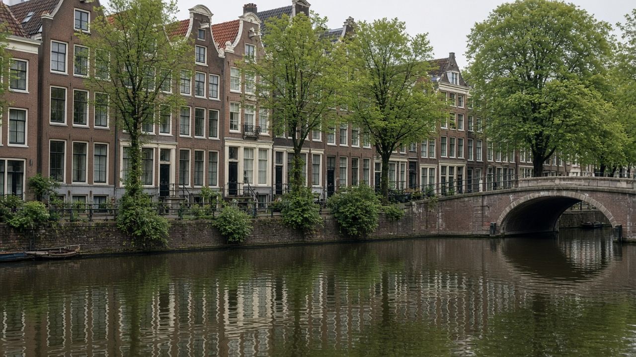 Amsterdam canal lined with brick townhouses and a small arched bridge